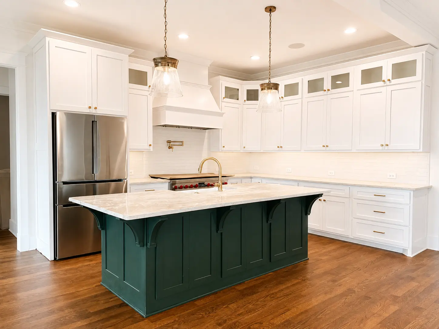 White kitchen cabinetry with a deep green custom island and brass fixtures