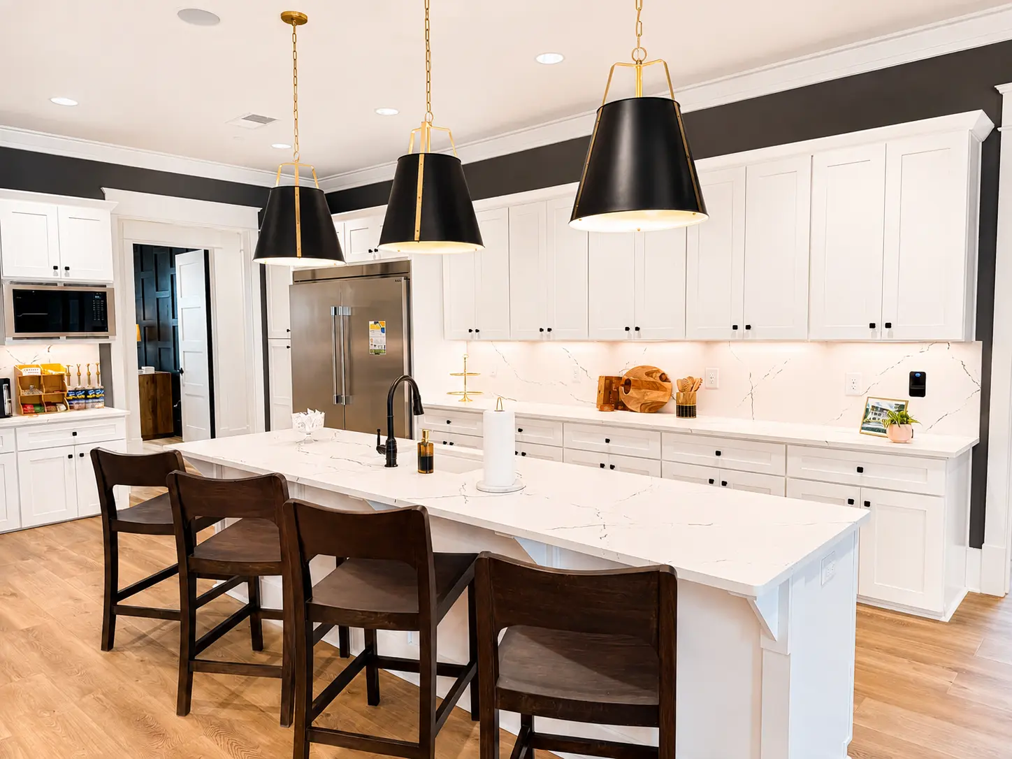 White kitchen with quartz island and black pendant lighting